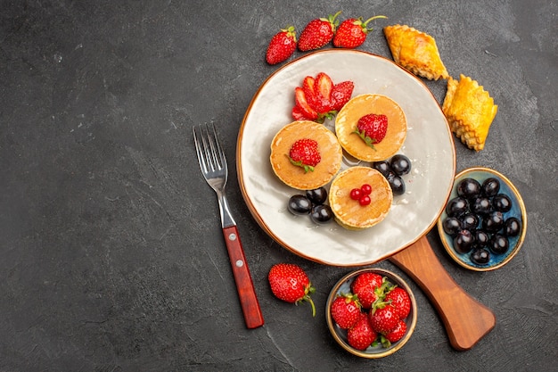 Top view little yummy pancakes with fruits on dark surface pie fruits cake