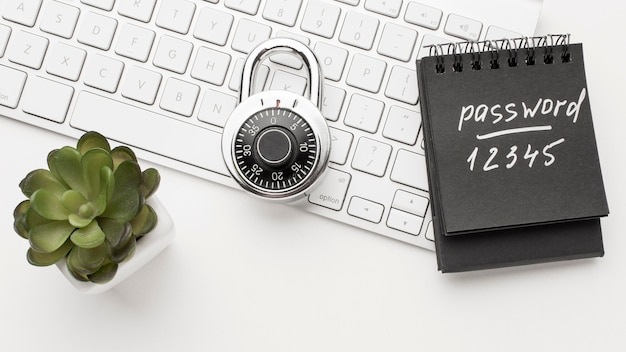 Top view of lock on keyboard with plant and notebook