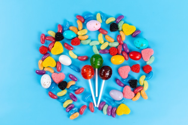 Free photo a top view lollipops and marmalades colorful tasty on blue, candy sugar children rainbow