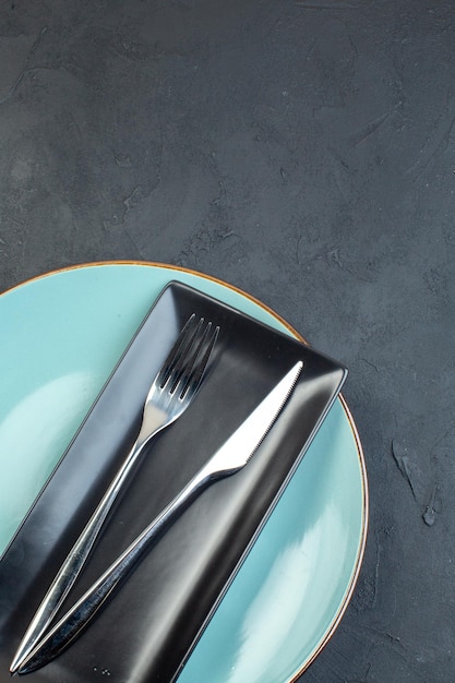 Free photo top view long black plate with blue plate fork and knife on dark surface