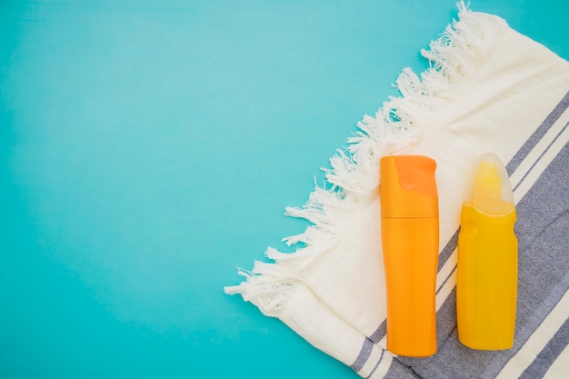 Top view of lotions and towel on blue surface