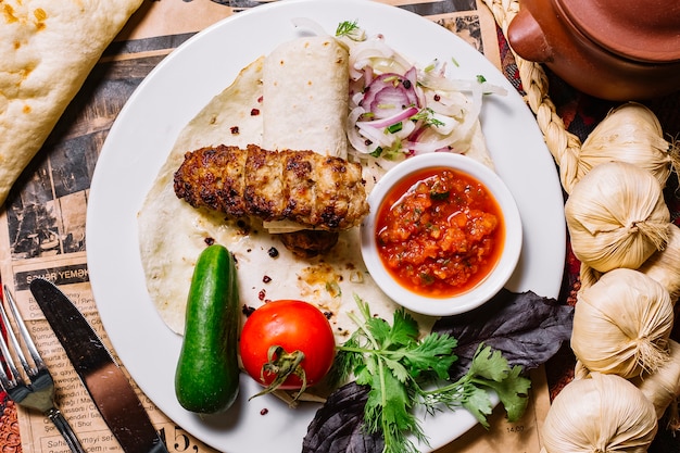 Top view lula kebab in pita bread with vegetables and sauce