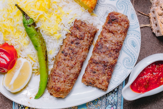 Top view lula kebab with rice and vegetables with a slice of lemon