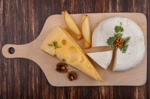 Top view maasdam and feta cheese with nuts on a stand  on a wooden background