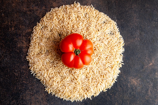 Top view macaroni in a circle form with tomato on them on dark textured background. horizontal