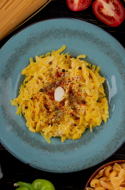 Top view of macaroni pasta in plate with cut tomato and pepper