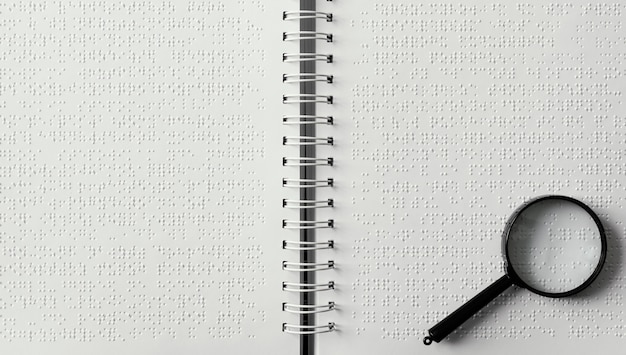 Free photo top view magnifying glass on braille notebook