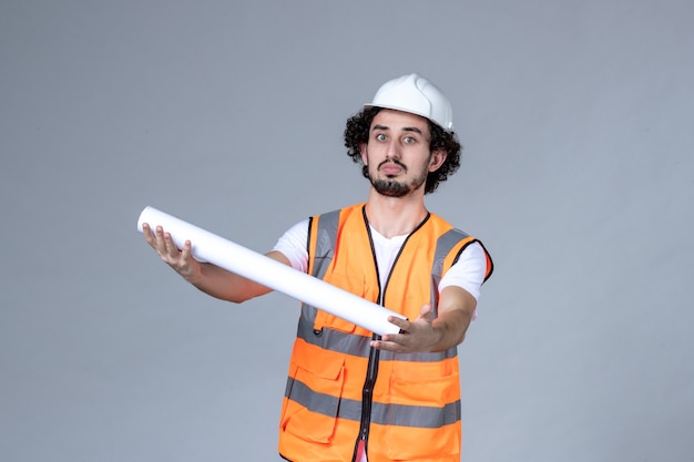 Top view of male constructor in warning vest wearing safety helmet and giving blank on gray wave wall