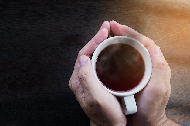 Top view of man hands holding hot coffee mug