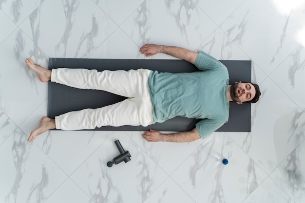 Free photo top view man laying on yoga mat