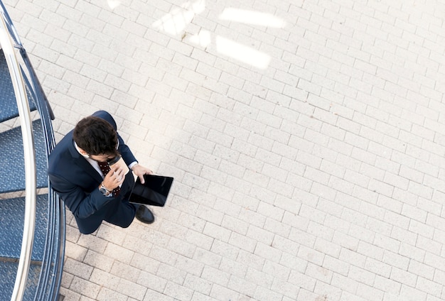 Free photo top view man with tablet drinking coffee