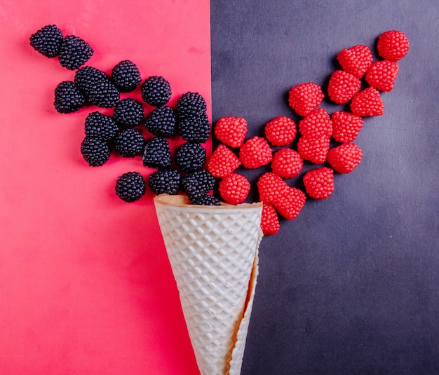 Free Photo top view marmalade in the form of raspberries on a black background and blackberries on a red background with a waffle cone