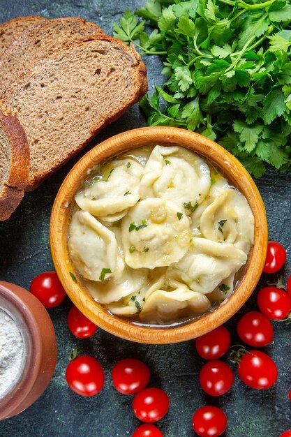 Top view meat dumplings with fresh cherry tomatoes bread and greens on dark surface