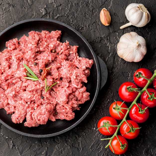 Top view of meat on plate with garlic and tomatoes