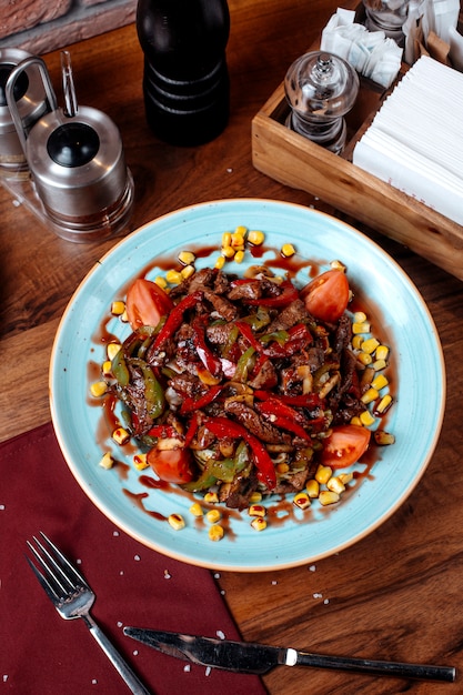 Top view of meat salad with tomato pepper and corn on a plate