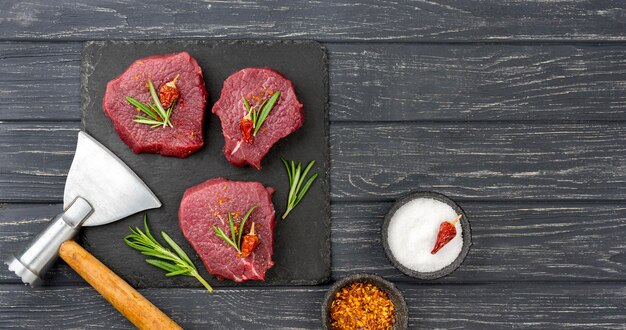 Top view of meat on slate with herbs