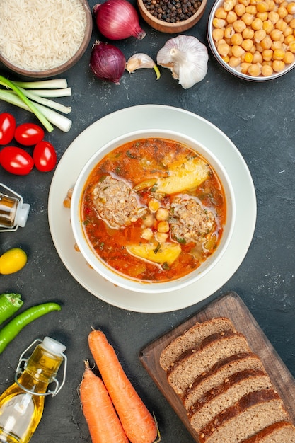 Top view meat soup with bread loafs and seasonings on a dark background