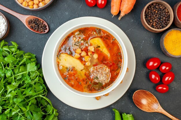 Top view meat soup with greens and seasonings on dark background