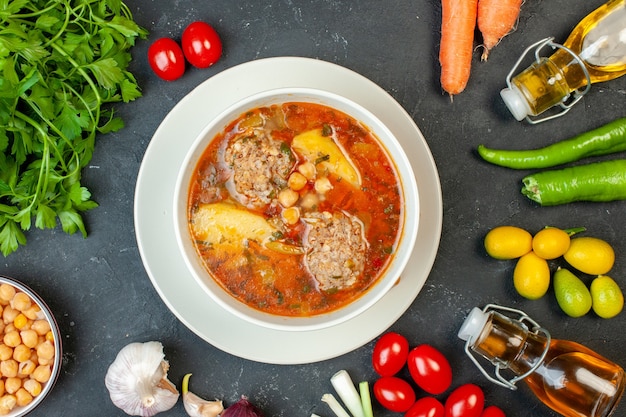 Top view meat soup with greens and vegetables on dark gray background