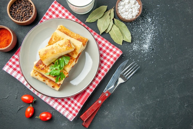 Top view meat stuffed blini on round plate lemon fork bay leaves on table