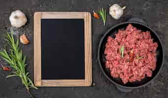 Free photo top view of meat with herbs and blackboard