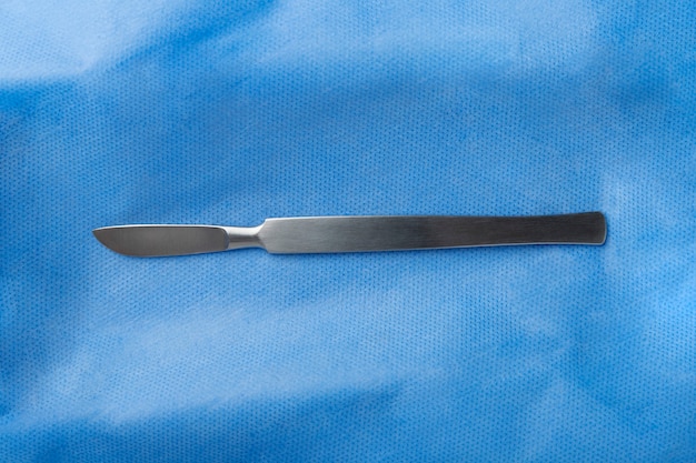 Free photo top view of medical scalpel on blue tissue