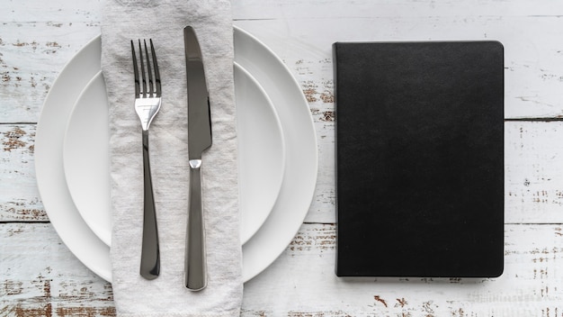 Free photo top view of menu book with plates and cutlery