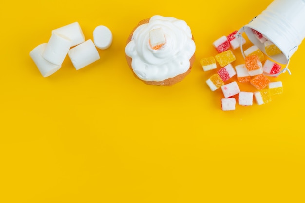 A top view meringues and marshmallows with marmalade on yellow, sugar sweet candy color