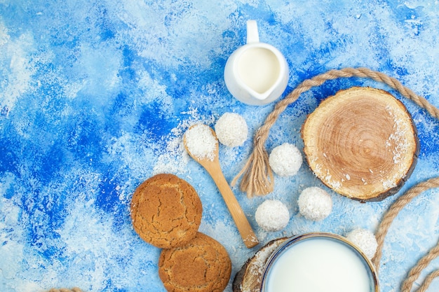 Free photo top view milk bowls wood boards coconut balls coconut powder in wooden spoons rope cookies on blue white background