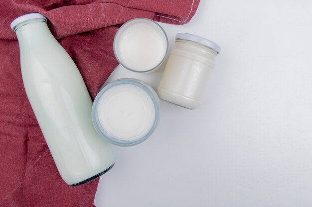 Top view of milk products as milk sour clotted milk and cream on bordo cloth and white background with copy space