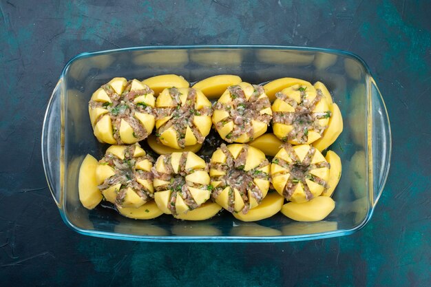 Top view of minced meat inside potatoes on dark surface