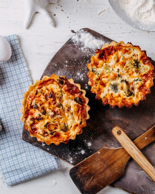 Top view of mini pie with meat and vegetables on a wooden cutting board