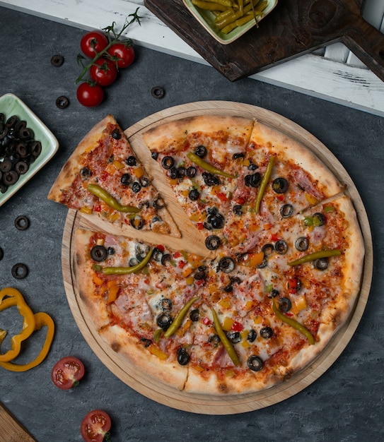 Top view mixed ingredient pizza cut into slices.