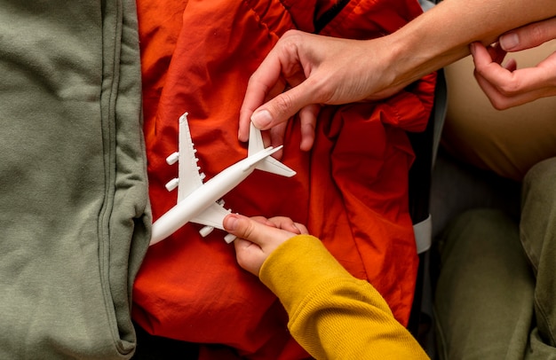 Free photo top view of mother and child putting airplane figurine in luggage