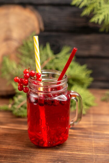 Top view of natural organic fresh currant juice in a bottle served with tubes on a wooden table