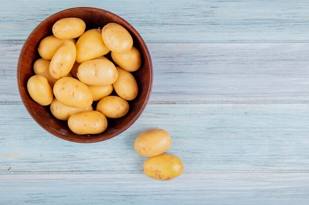 Top view of new potatoes in bowl and on wooden surface with copy space