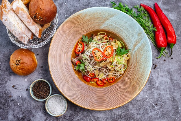 Top view of noodles with beef garnished, chili pepper onion and grated cheese