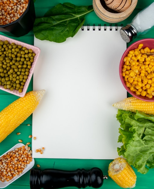 Free photo top view of note pad with vegetables and salt around on green surface with copy space