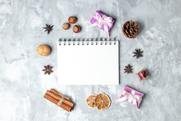 Top view notebook cinnamon sticks dried lemon slices anises on grey surface