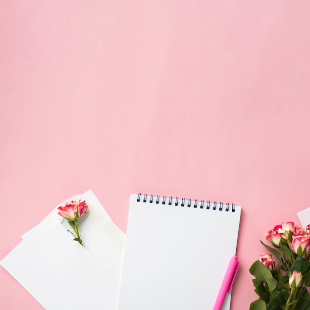 Top view on notebook on desk with bouquet of roses and copy space