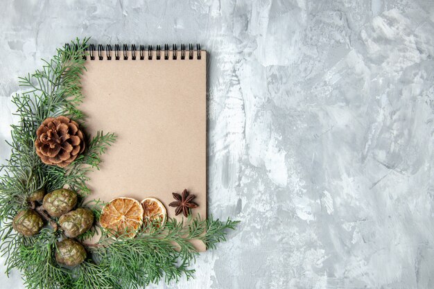 Top view notebook dried lemon slices anises pine tree branches on grey background with free space