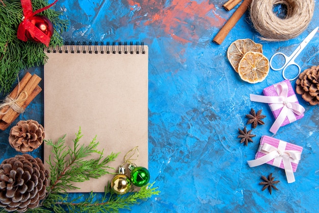 Top view a notebook pine tree branches pinecone star anises scissors straw thread on blue background free space