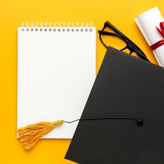 Top view of notebook with academic cap and glasses