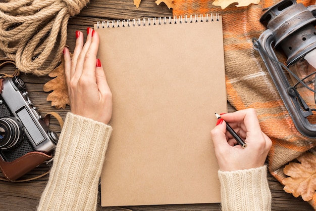 Top view of notebook with autumn leaves and camera