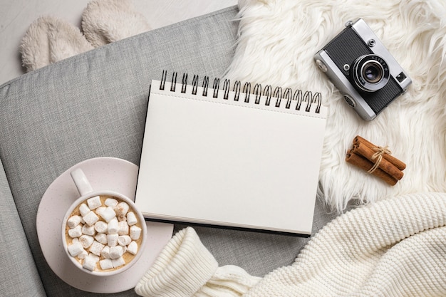 Free photo top view of notebook with camera and cup of hot cocoa with marshmallows