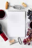 Free photo top view notebook with frame of grapes and wine