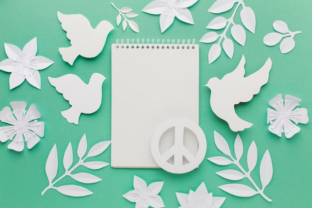 Free photo top view of notebook with paper doves and peace sign