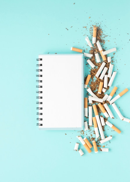 Free photo top view notebook with pile of cigarettes