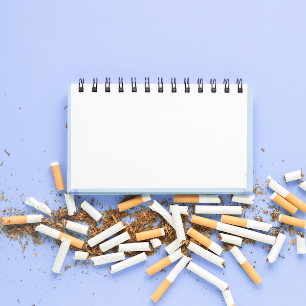 Free photo top view notebook with pile of cigarettes