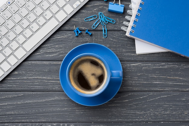 Free photo top view of notebook on wooden desk with coffee cup and paper clips